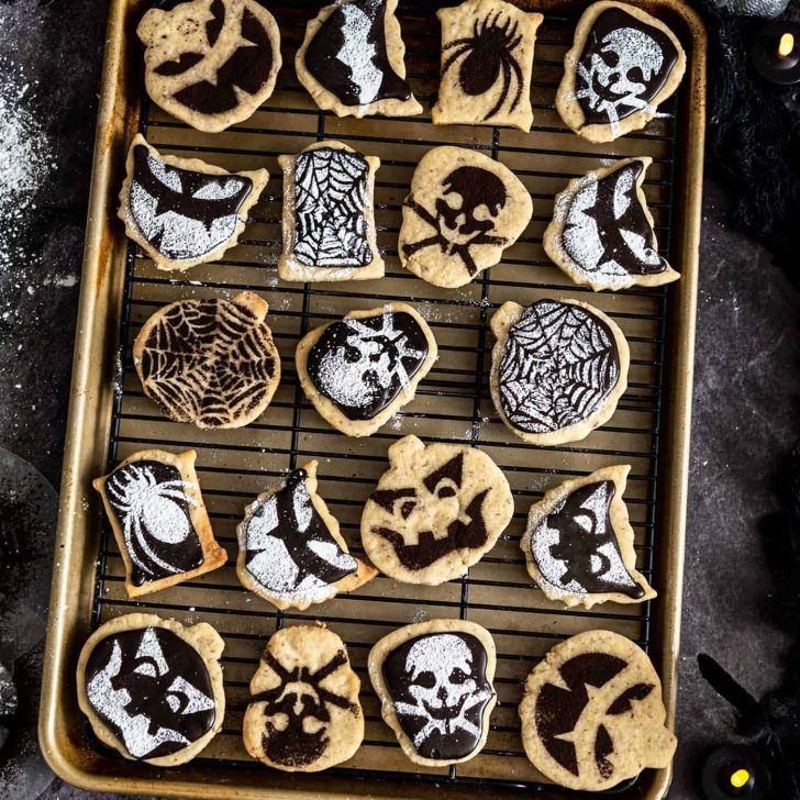 Baking sheet and cooling tray with halloween-stenciled shortbread cookies on it