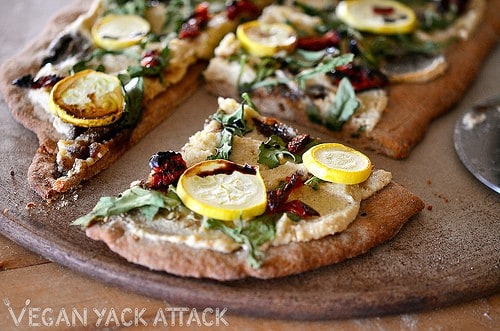 Image of Rustic Arugula Flatbread on a pizza stone with slice cut out