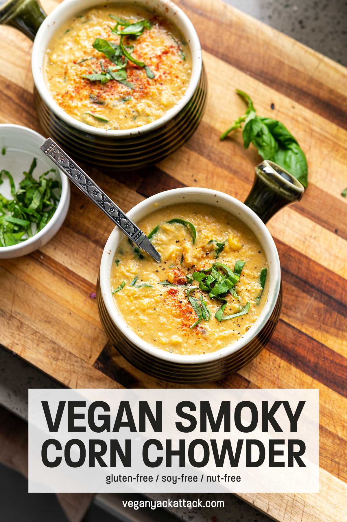 Bowl of corn chowder topped with basil on a cutting board with text overlay "vegan smoky corn chowder"