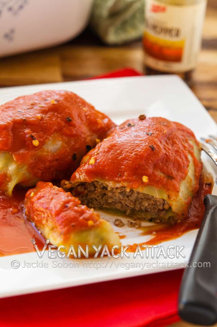 Vegan cabbage roll with slice out of the front on a white plate