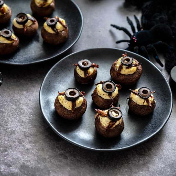 Tofu-Stuffed mushrooms on black plates with halloween decorations