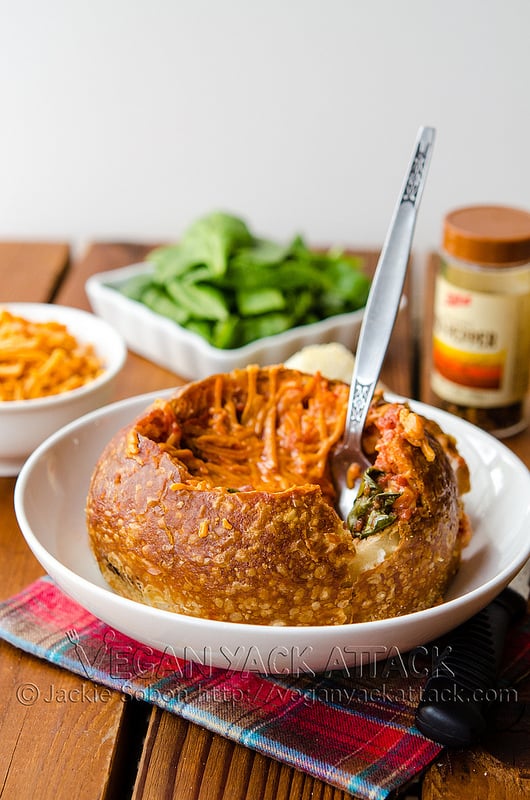 A comforting meal of tomato spinach soup in a toasted sourdough bowl, topped with melted cheddar shreds; AKA the Tomato Spinach Grilled Cheese Bread Bowl!
