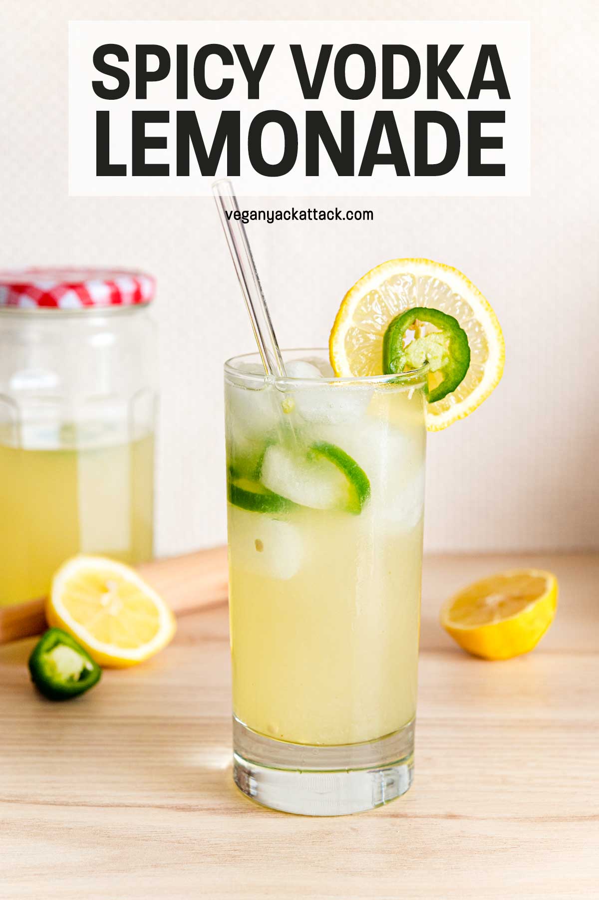 One glass of lemonade with jalapeño slices and ice in it, plus a jar of mix in the background