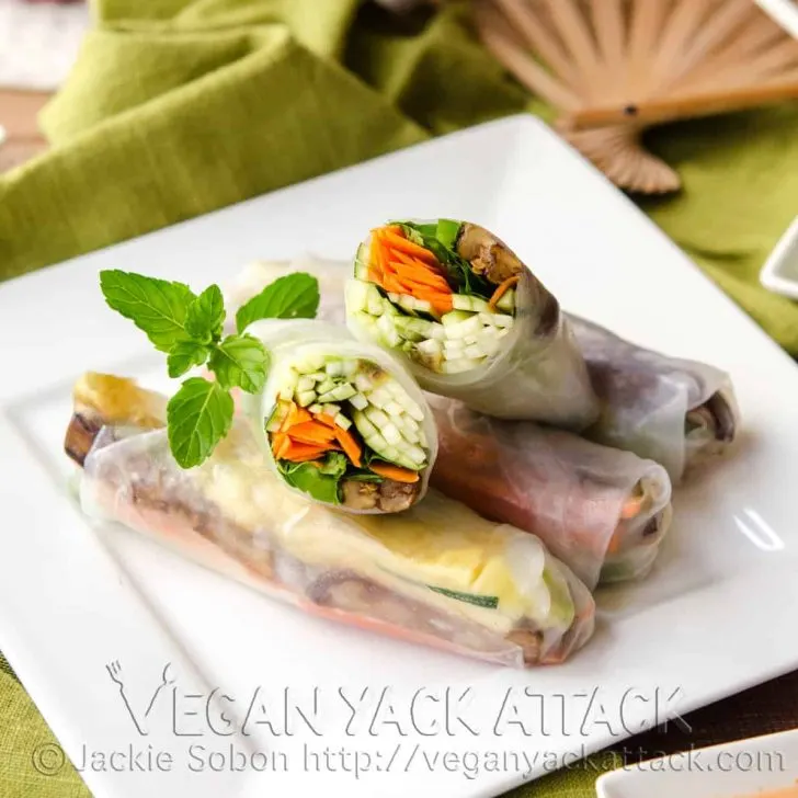 Grilled Eggplant Spring Rolls on a square white plate with fan in the background