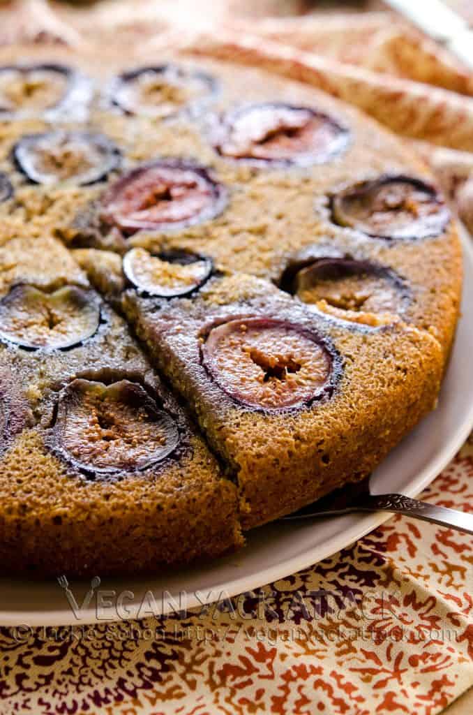 A simple vanilla cake with figs baked into it, with a slice being cut out