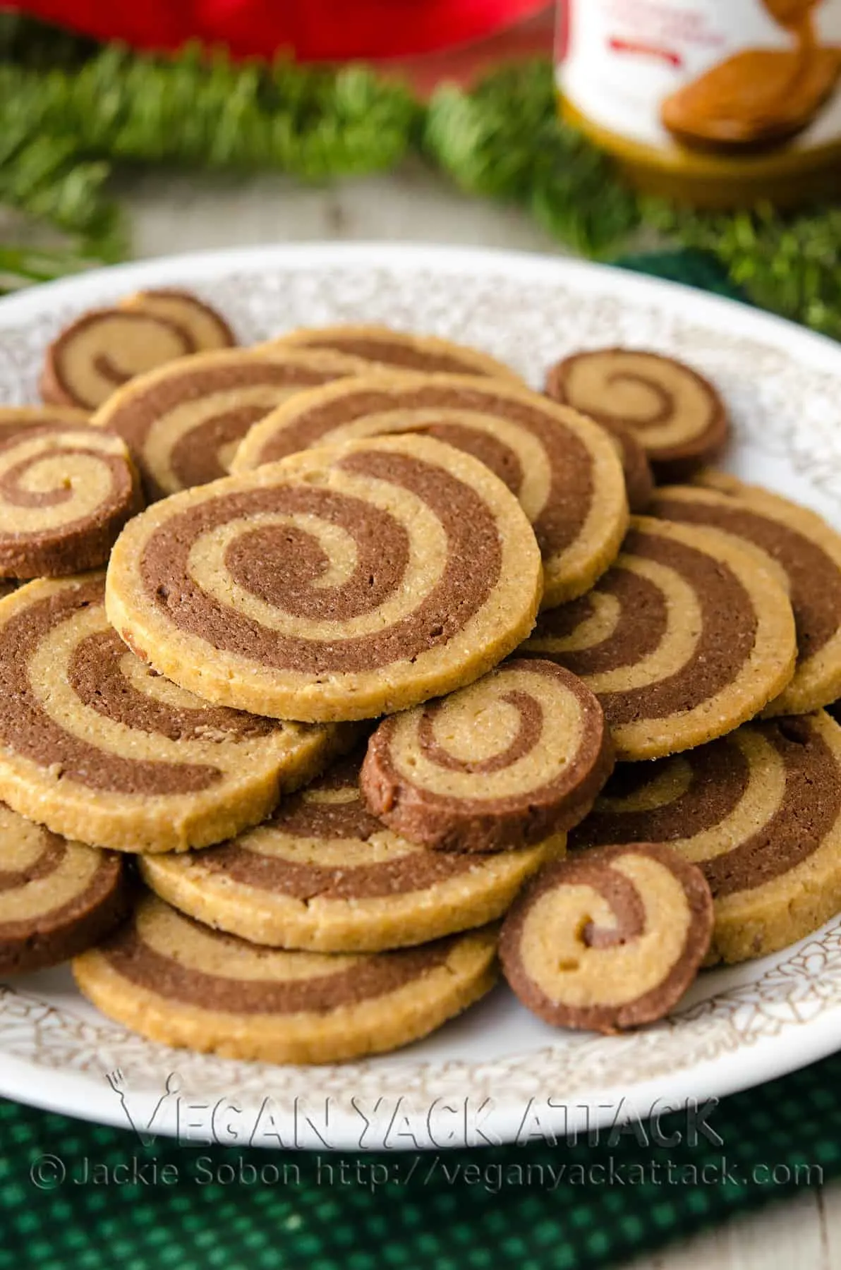 Biscoff Chocolate Pinwheel Cookies on a white plate surrounded by pine branches