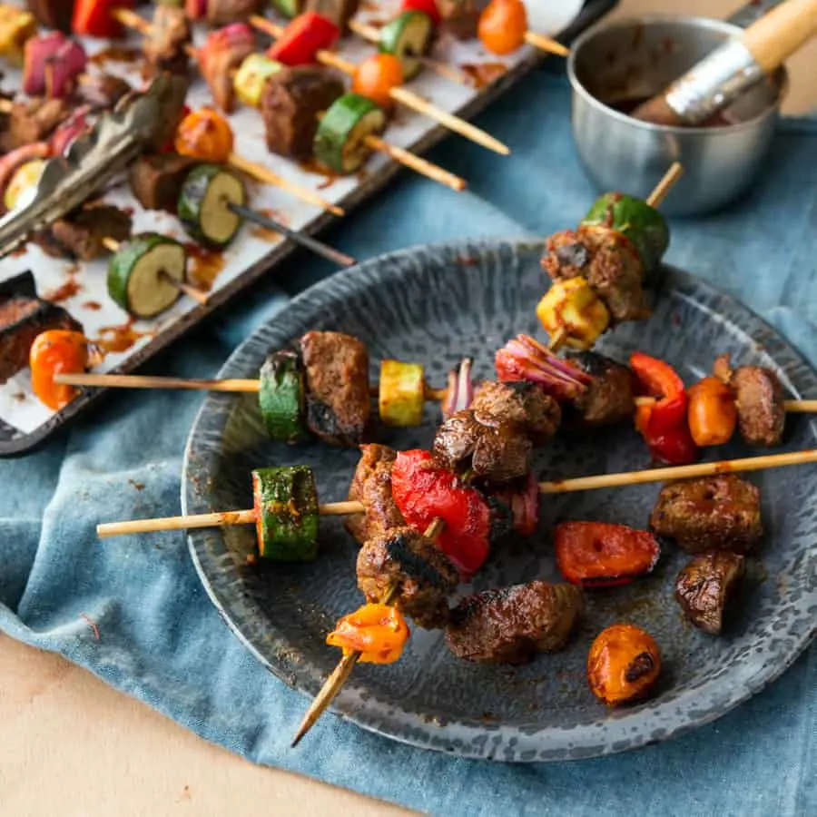Seitan and veggie skewers on an enamel plate and denim linen