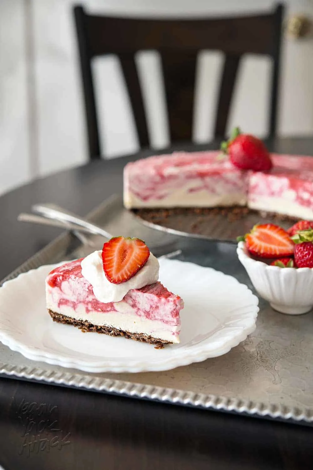 Slice of strawberry swirl cheesecake on a white plate