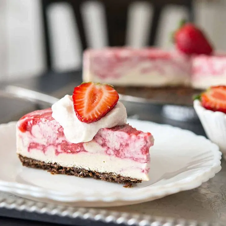 Slice of strawberry swirl cheesecake on a white plate