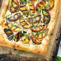 Grilled peaches and cream pastry on a baking sheet lined with parchment paper