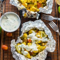 Grill packet filled with curry cauliflower veggie mixture topped with yogurt sauce
