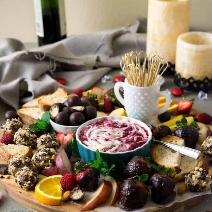 Image of elaborate dessert platter, featuring vegan sweets, raspberry merlot creme fraiche, with wine and candles in the background