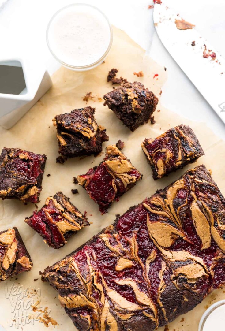 Image of brownies on parchment paper, with peanut butter and jelly swirled into the tops