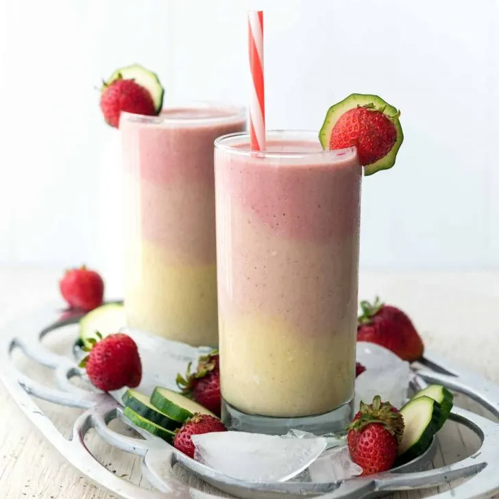 Image of multi-colored smoothies, layered into two glasses, on a platter.