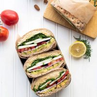 Sliced rosemary chickpea salad sandwiches in a lunch container on a white background