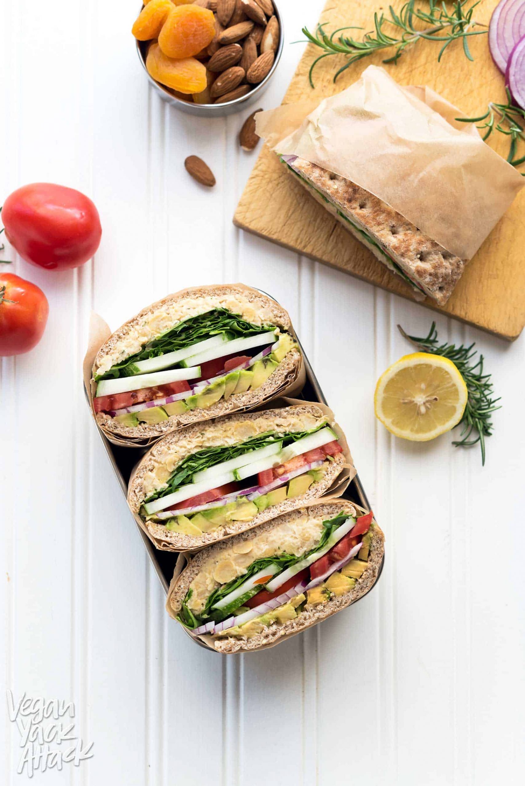 Sliced rosemary chickpea salad sandwiches in a lunch container on a white background