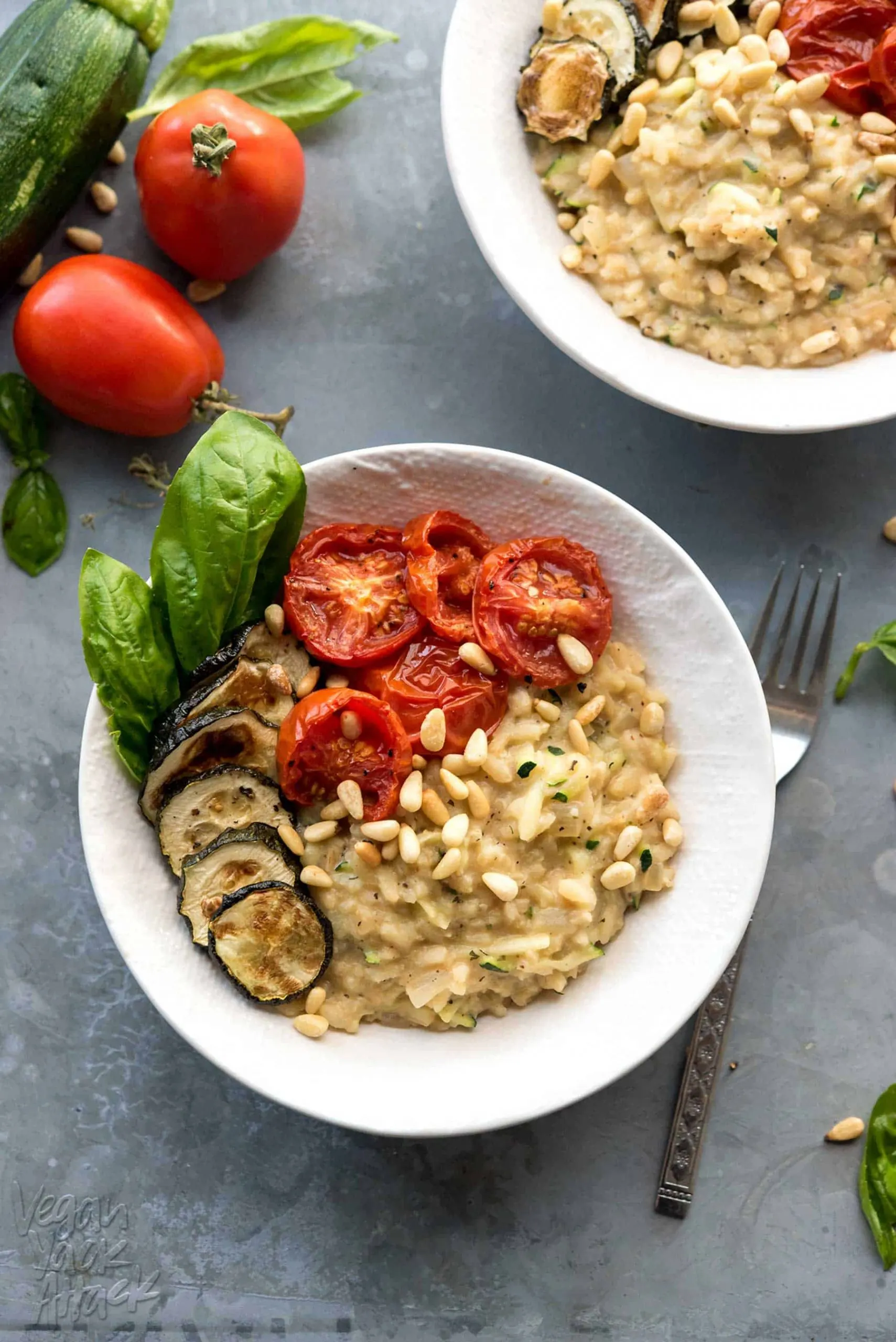 risotto in white bowl, topped with roasted zucchini and tomatoes