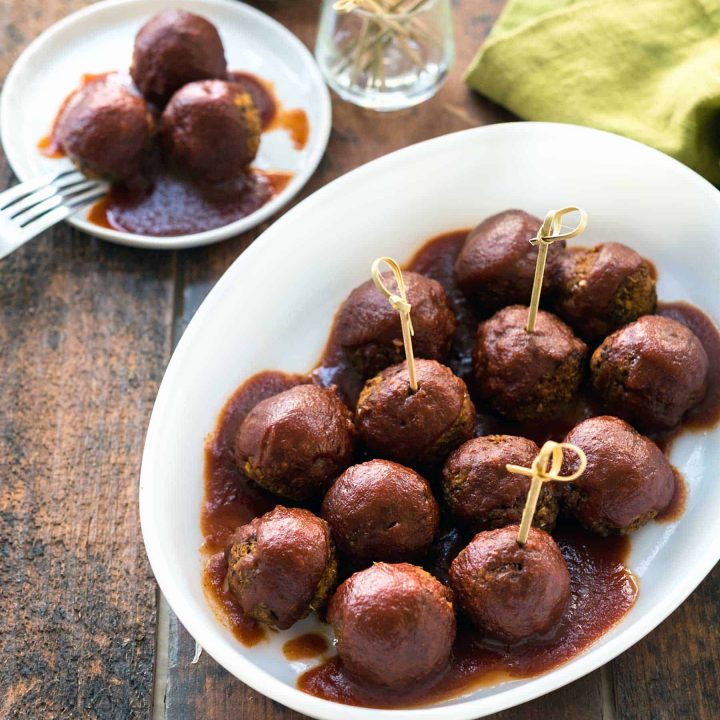 Image of lentil meatballs covered in barbecue sauce in a white dish