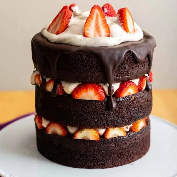 Image of chocolate layer cake with strawberries and vanilla mousse on a white cake stand