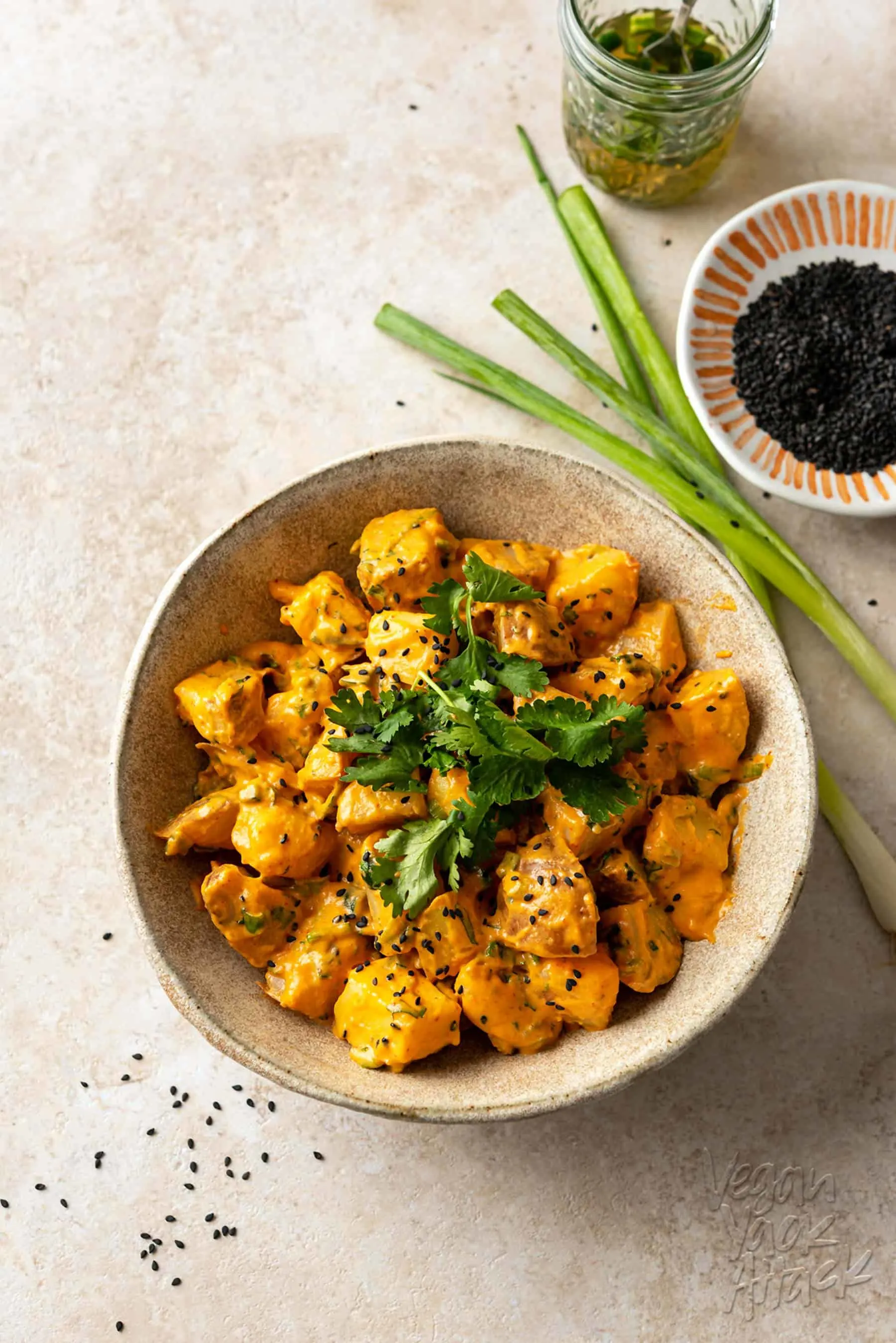 Large ceramic bowl filled with sriracha potato salad that is topped with sesame seeds and cilantro