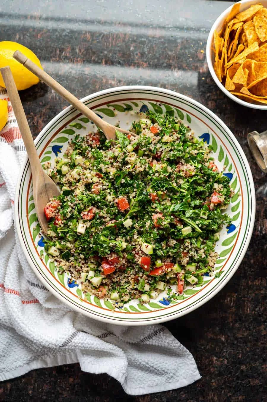 Image of kale quinoa tabbouleh salad in a large ceramic bowl, on granite countertop.