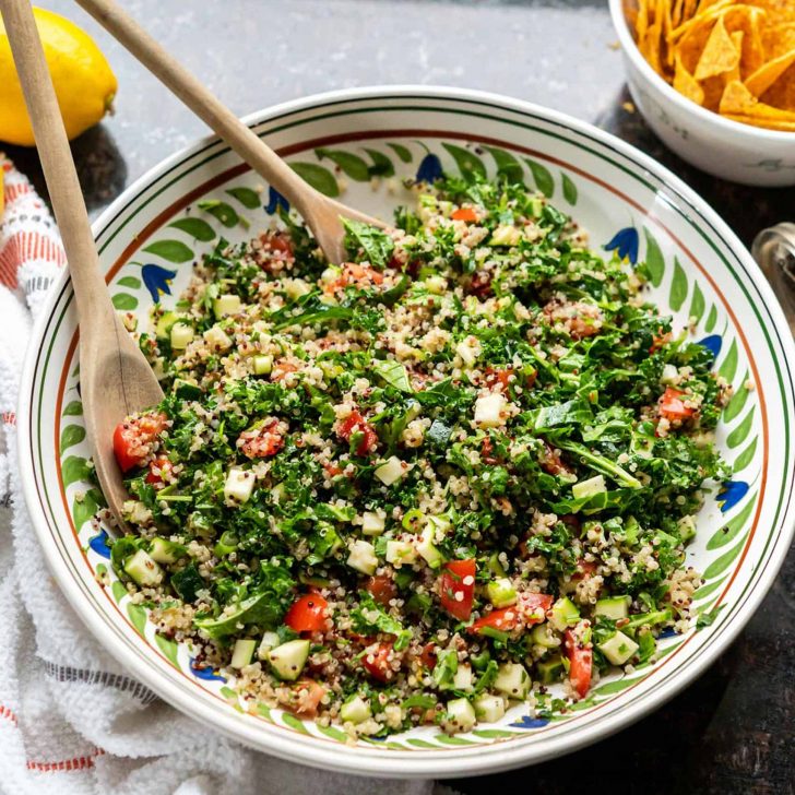 Image of kale quinoa tabbouleh salad in a large ceramic bowl, on granite countertop.