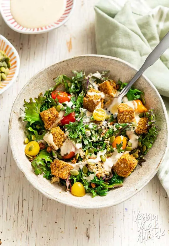 Close up shot of Comforting Tempeh Kale Salad in a ceramic bowl with fork