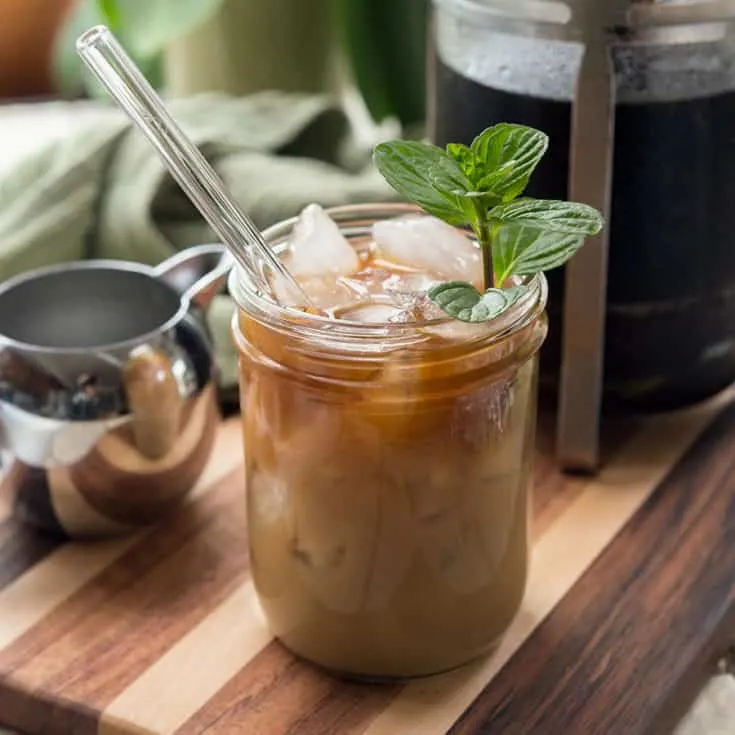 Glass jar filled with mint mocha cold brew on a cutting board