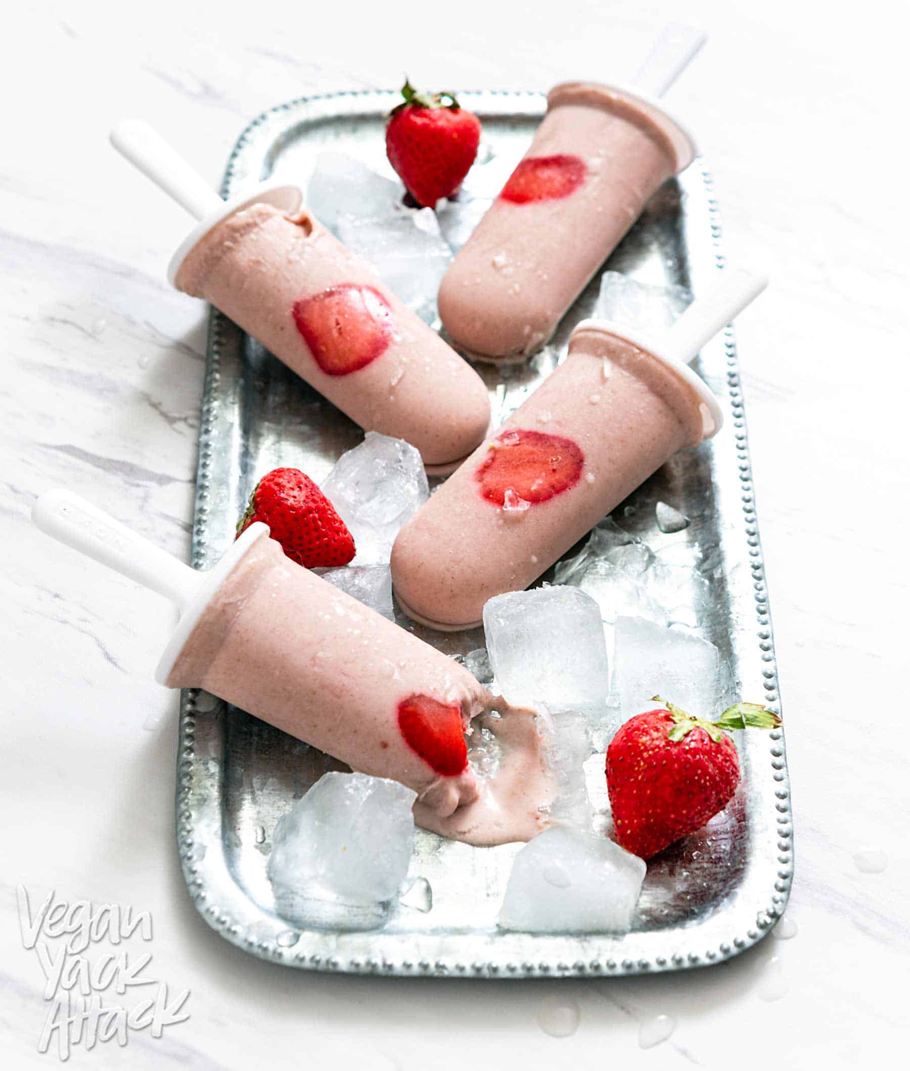 Strawberry Oat Milk Popsicles on a metal platter with ice cubes