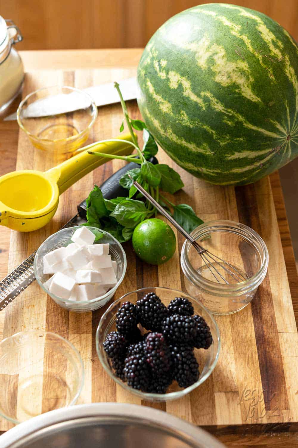 Watermelon, blackberries, vegan feta, lime, and basil on a cutting board