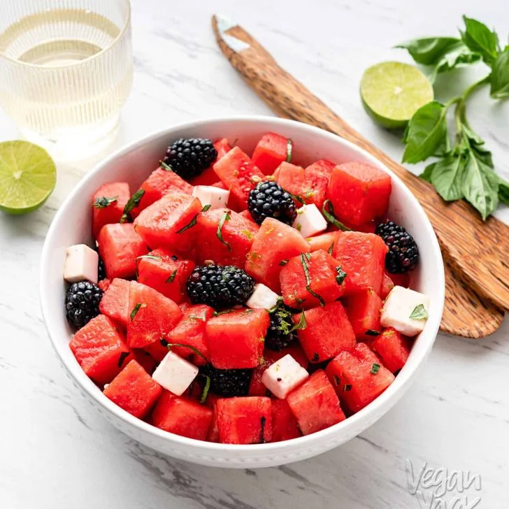 Watermelon Blackberry Feta Salad in a large white bowl with wooden tongs