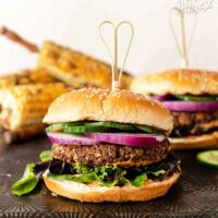 Veggie burger stacked with onion, cucumbers, mixed greens and bun