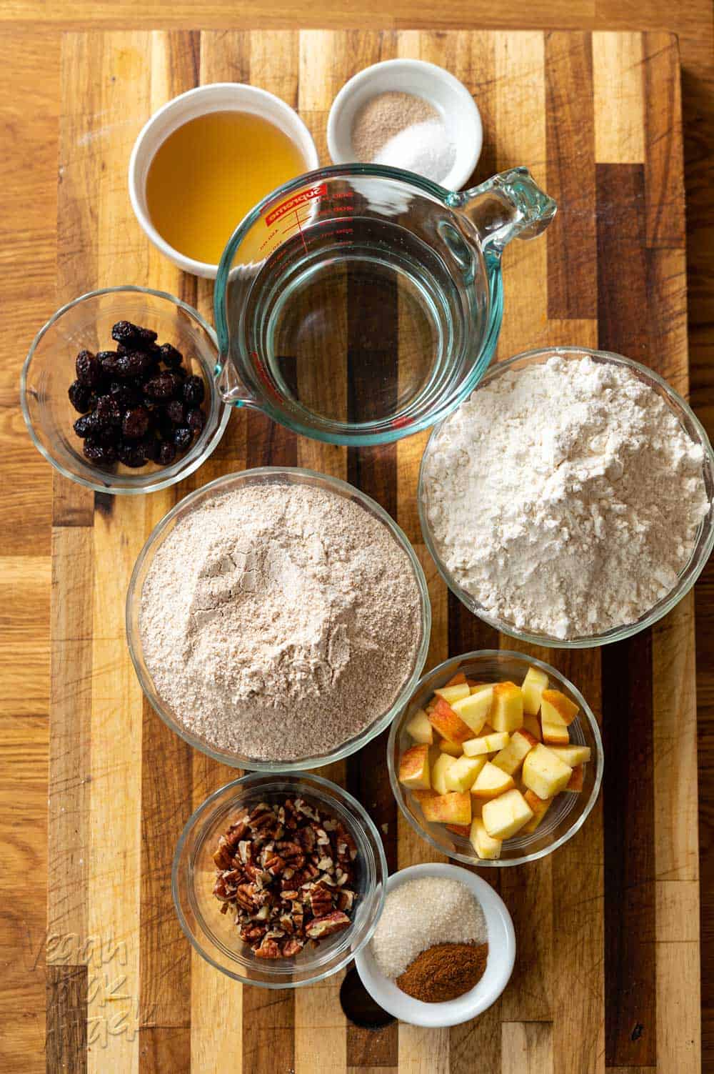 Flours, apple, pecans, craisins, water, and more, in ramekins on a cutting board