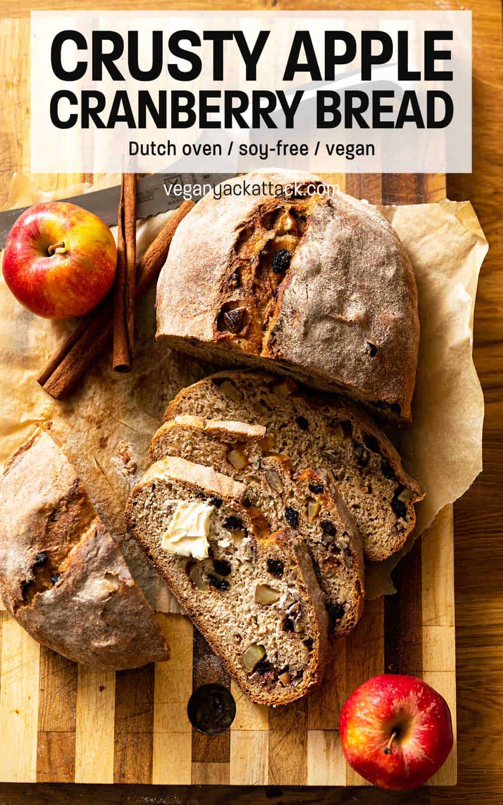 Loaf of whole wheat bread cut partially into slices on a cutting board with text reading "Crusty Apple Cranberry Dutch Oven Bread"
