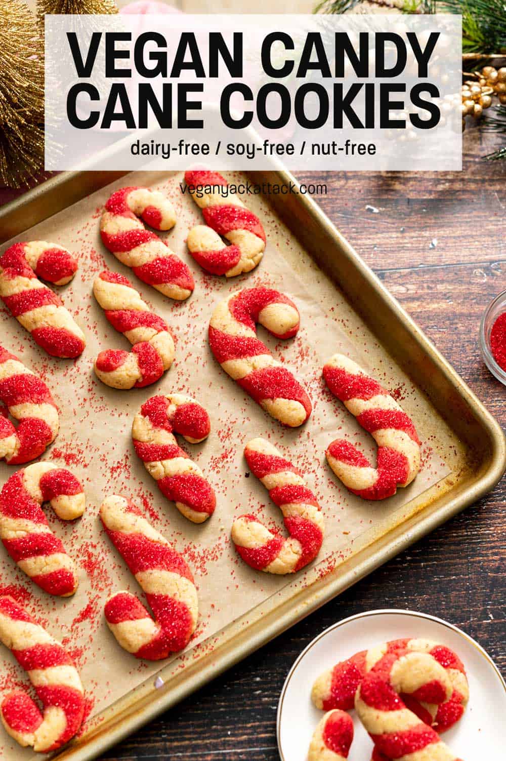 Candy cane-shaped cookies on a baking sheet next to colored sugar with text overlay "Vegan Candy Cane Cookies"