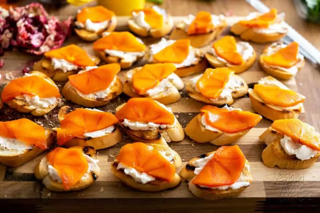 Crostini with vegan cream cheese and thinly sliced fuyu persimmon on top