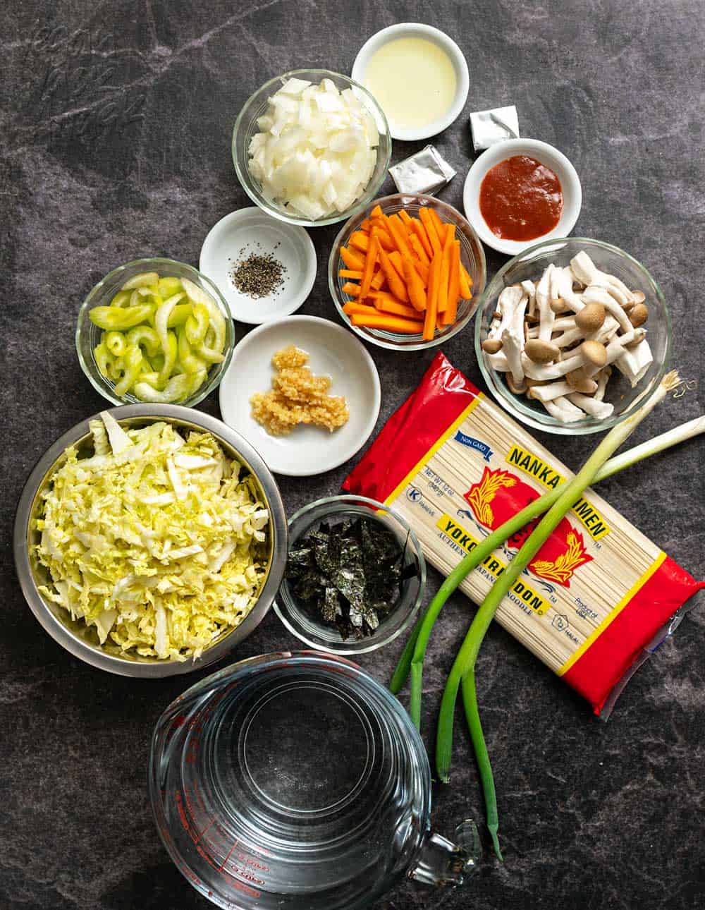 Noodles, veggies, and other ingredients for soup in bowls