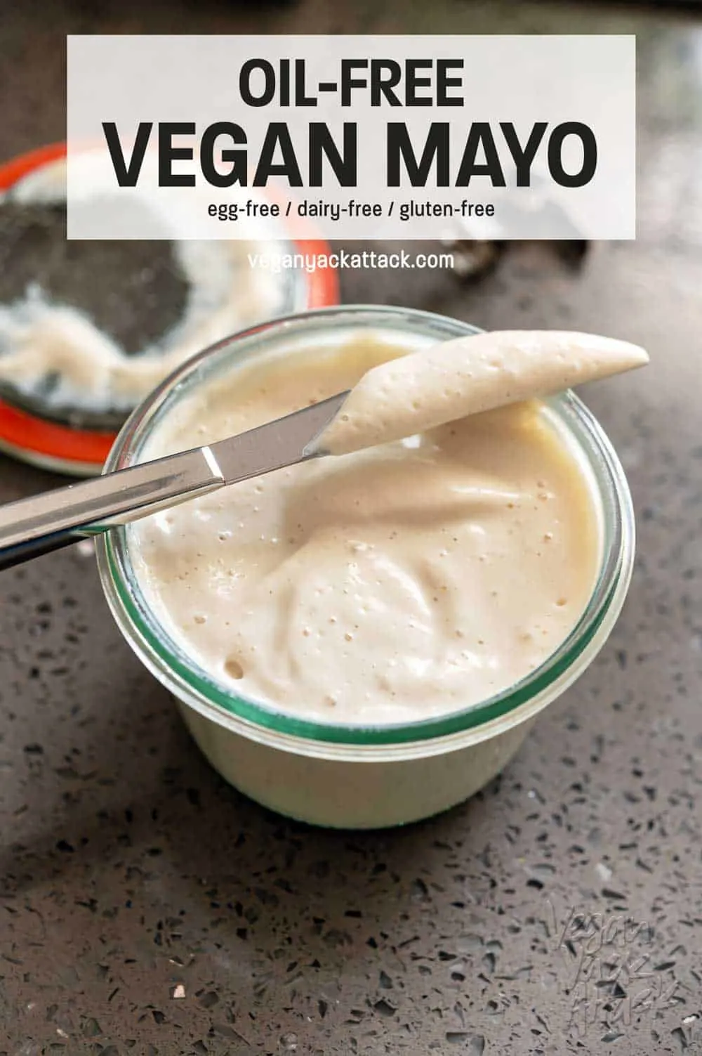Small jar of vegan mayo with butter knife on a grey quartz counter