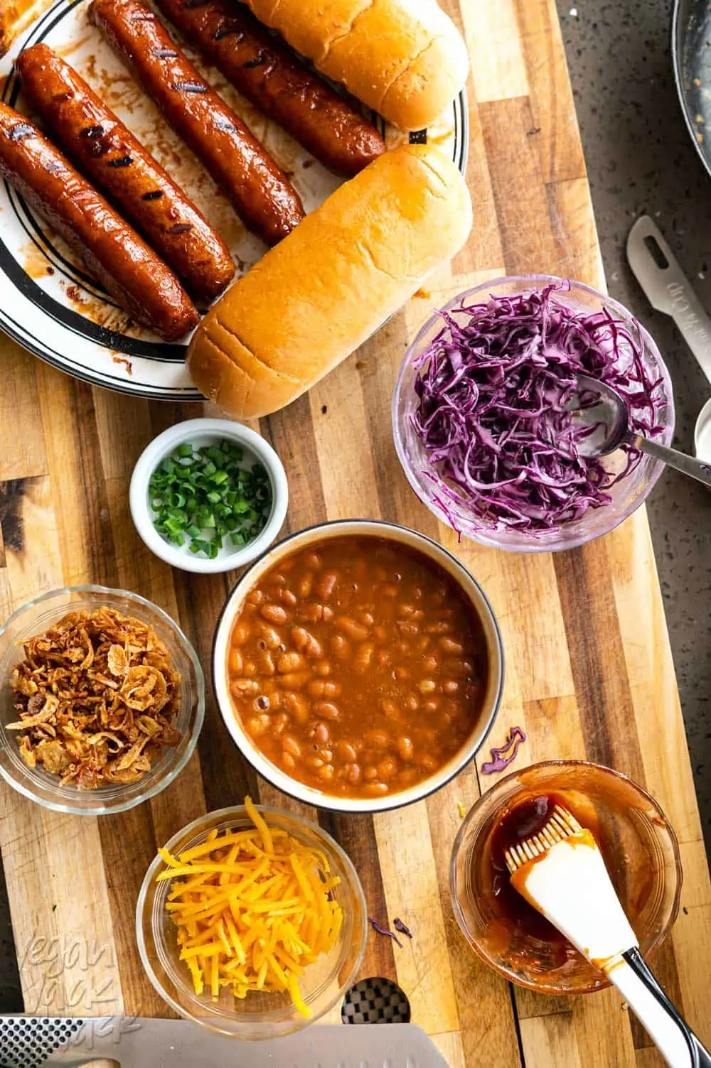 Beans, slaw, hot dogs, and other toppings on a cutting board
