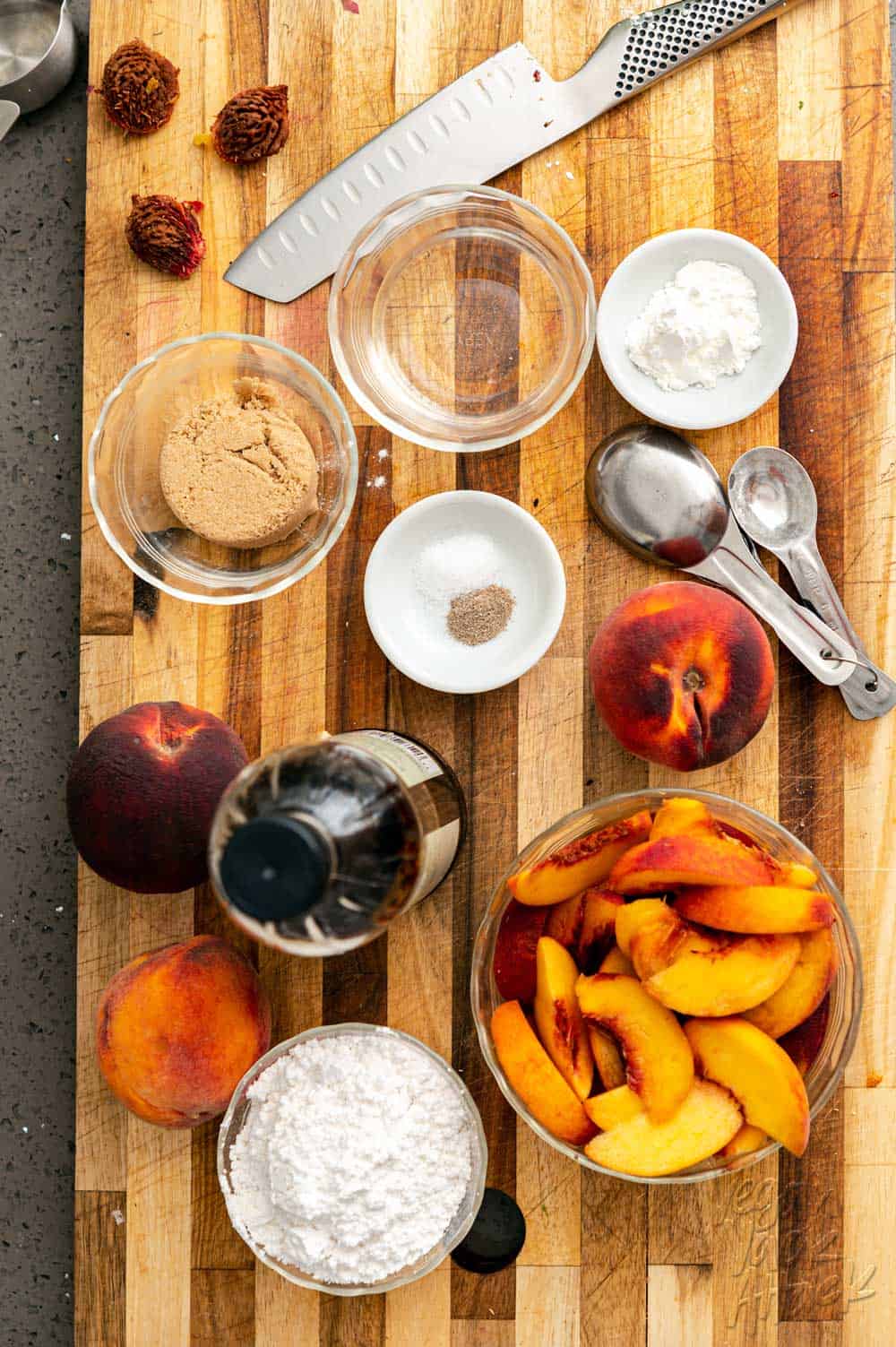 Ingredients measured out on a cutting board, including peaches, sugar, and more.