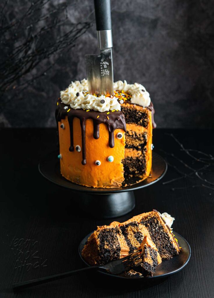 Orange frosting covered a marbled layer cake, with a knife sticking out of the top