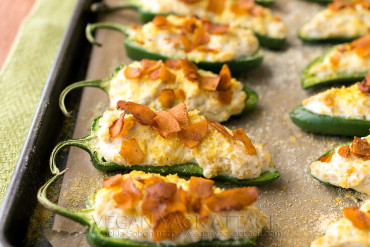 close up of jalapeño poppers on a baking sheet, topped with coconut bacon
