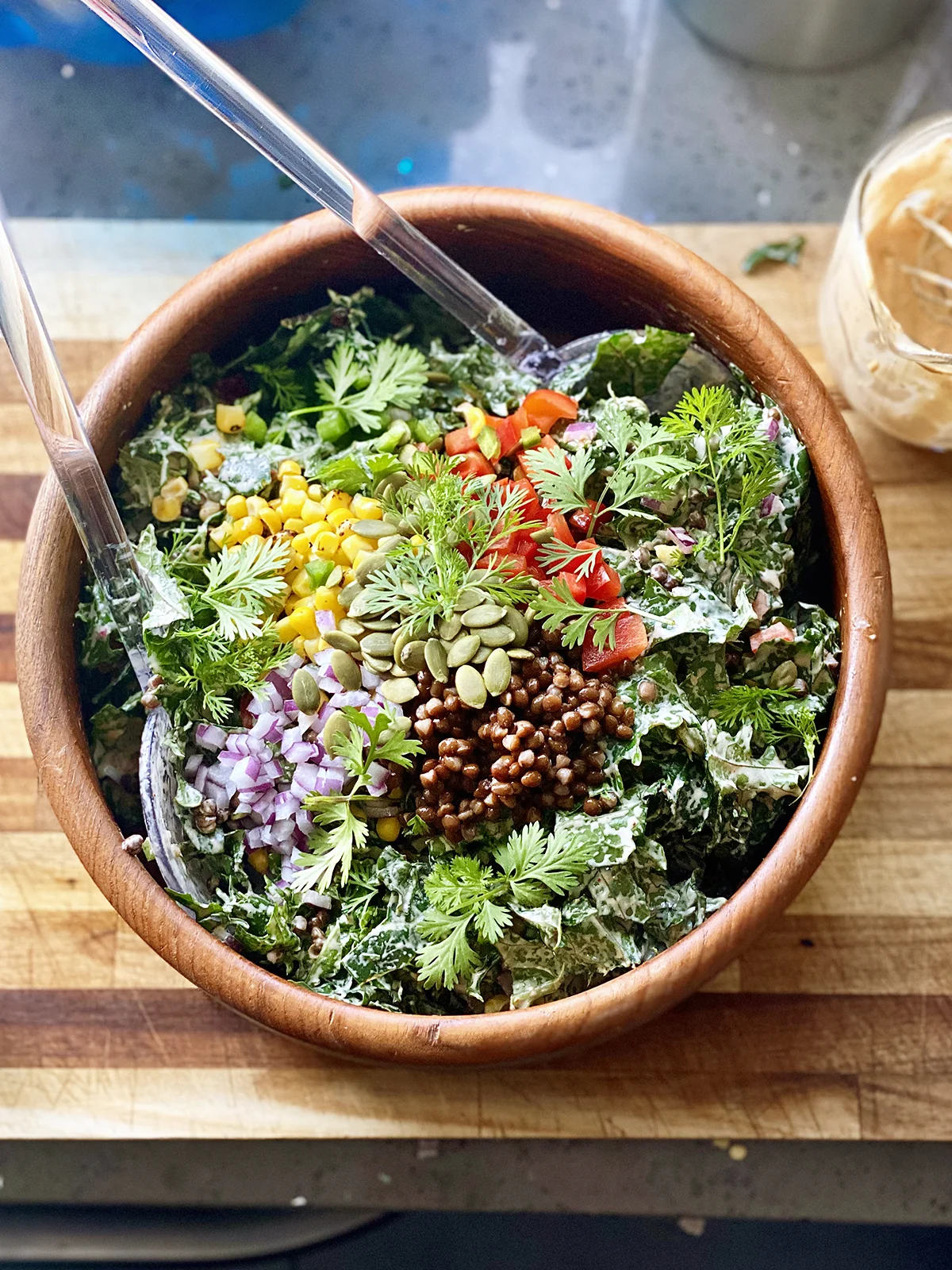 Vegan Southwest Kale Salad in a wood bowl on a cutting board