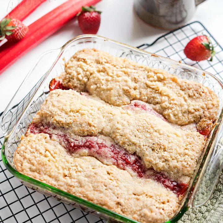 Strawberry rhubarb coffee cake in a glass casserole dish on a cooling rack