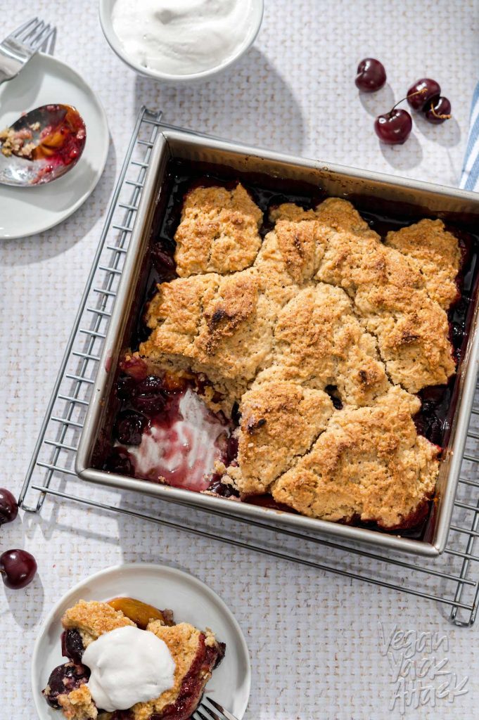 Square baking dish of fruit cobbler on a wire rack, on a white table cloth