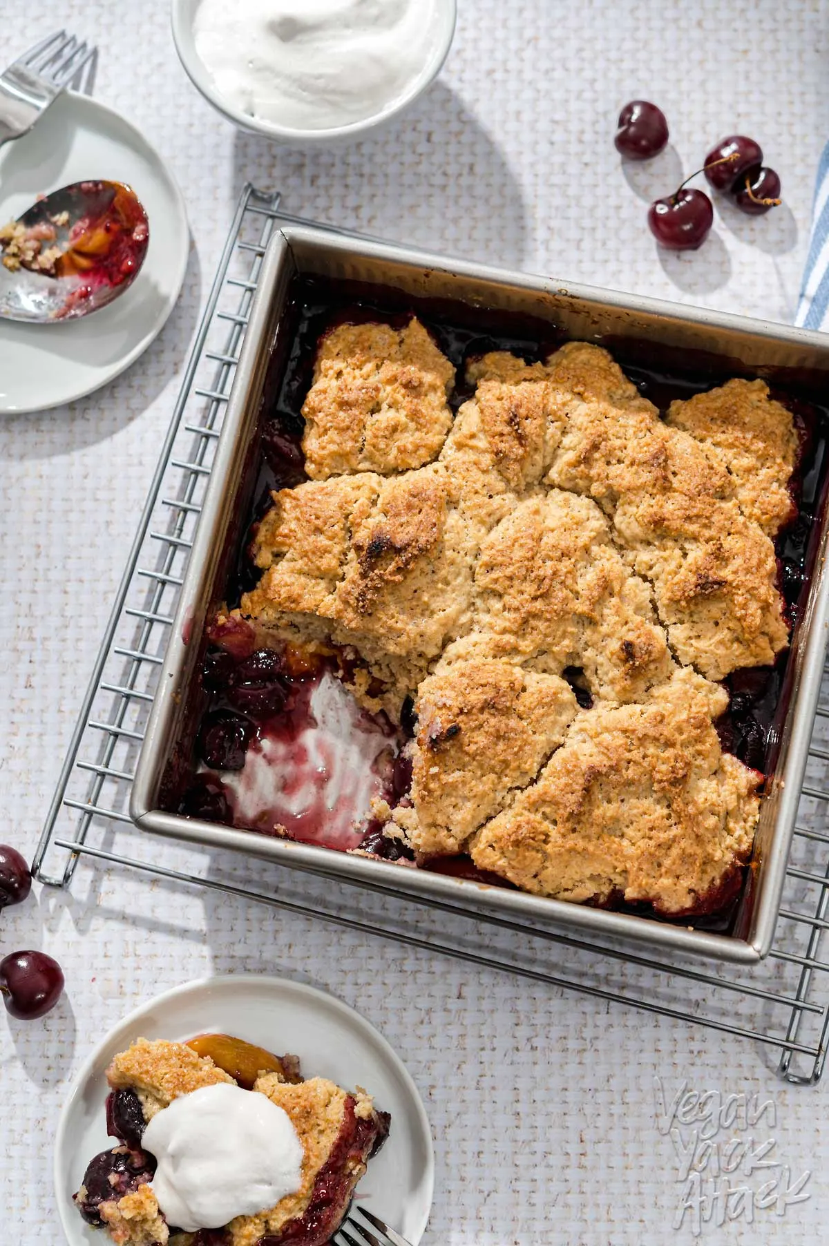 Square baking dish of fruit cobbler on a wire rack, on a white table cloth