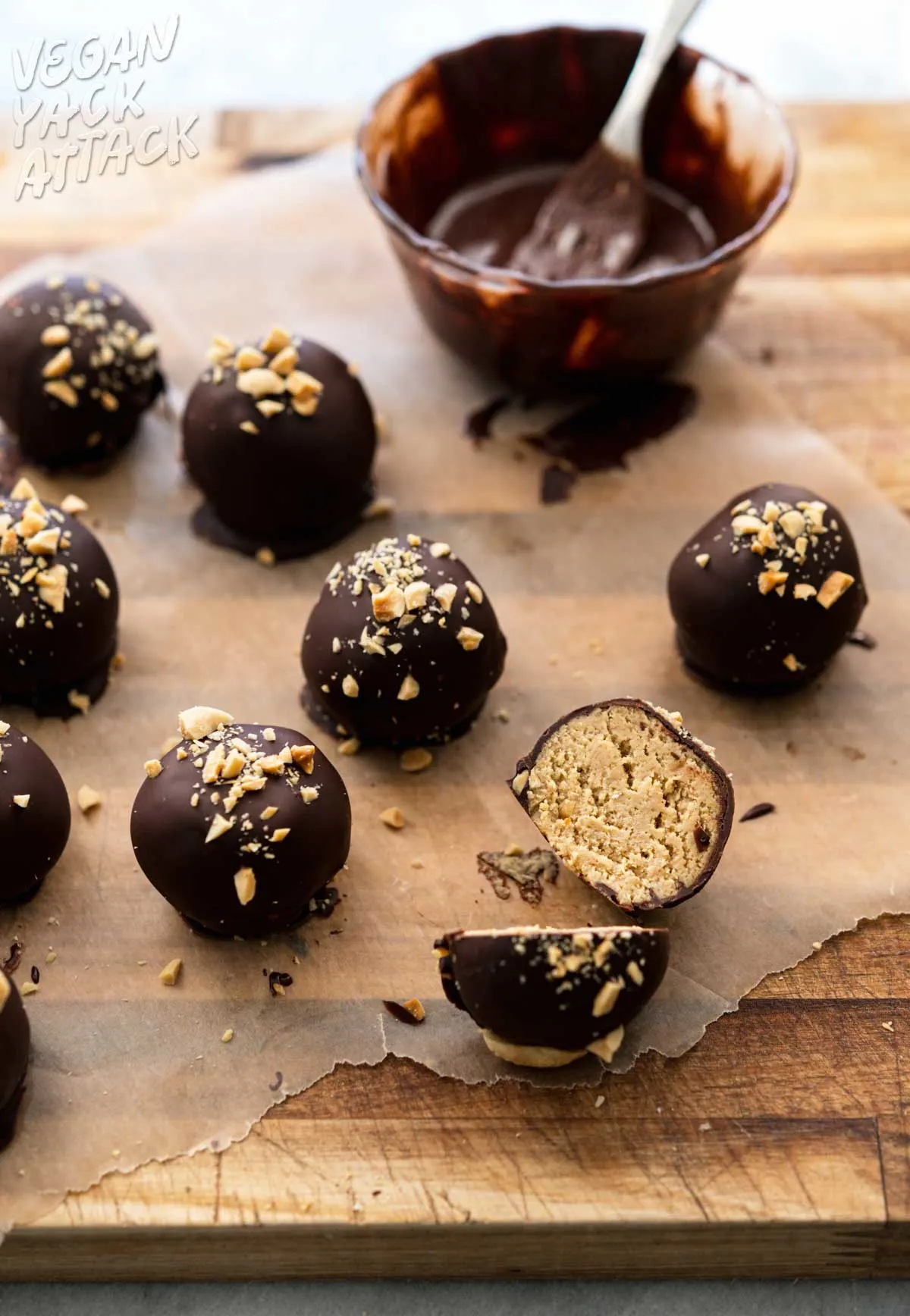 Chocolate-covered peanut butter bites on a cutting board next to melted chocolate