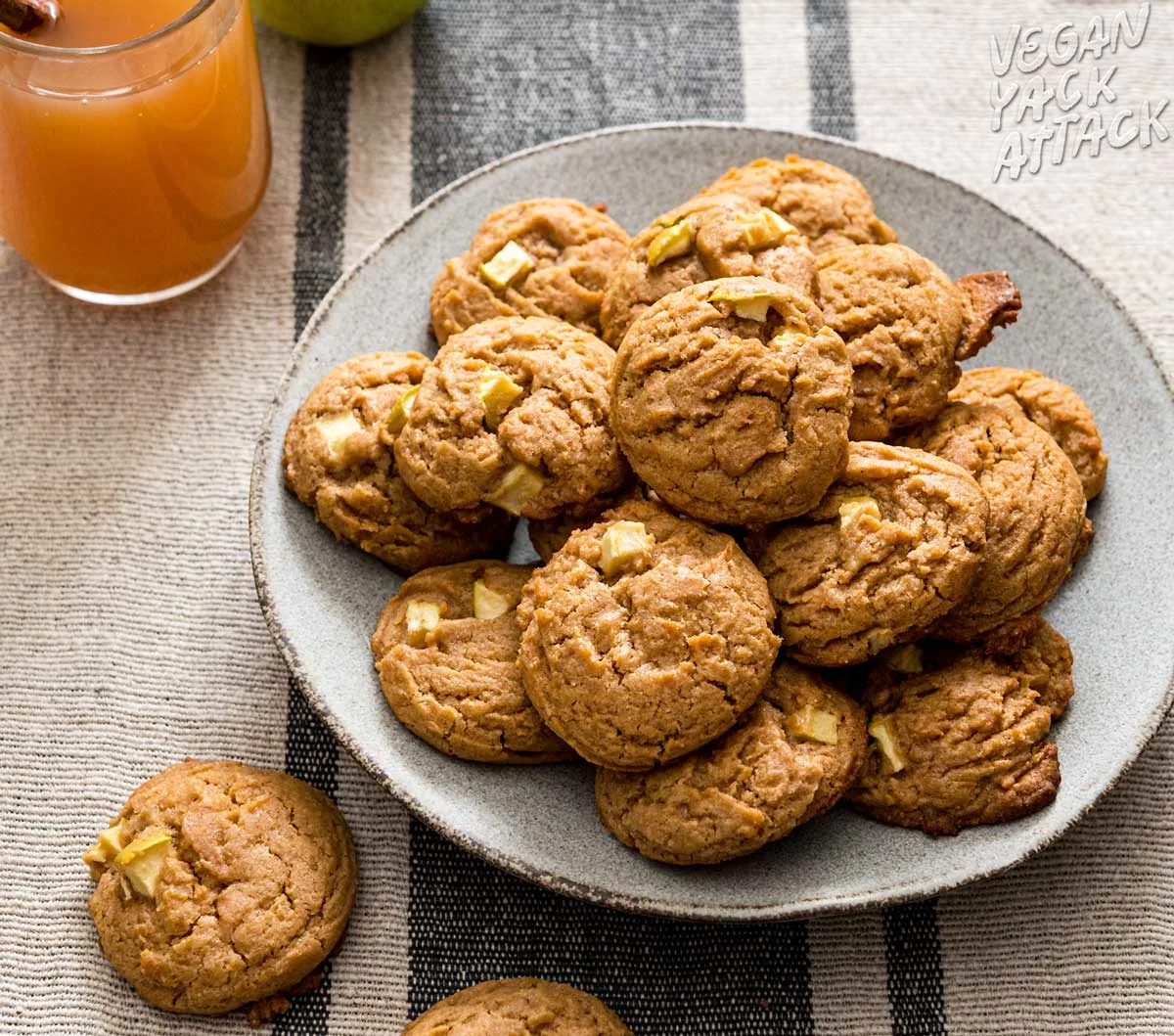 apple cider cookies in a pile on a grey plate next to a mug of cider