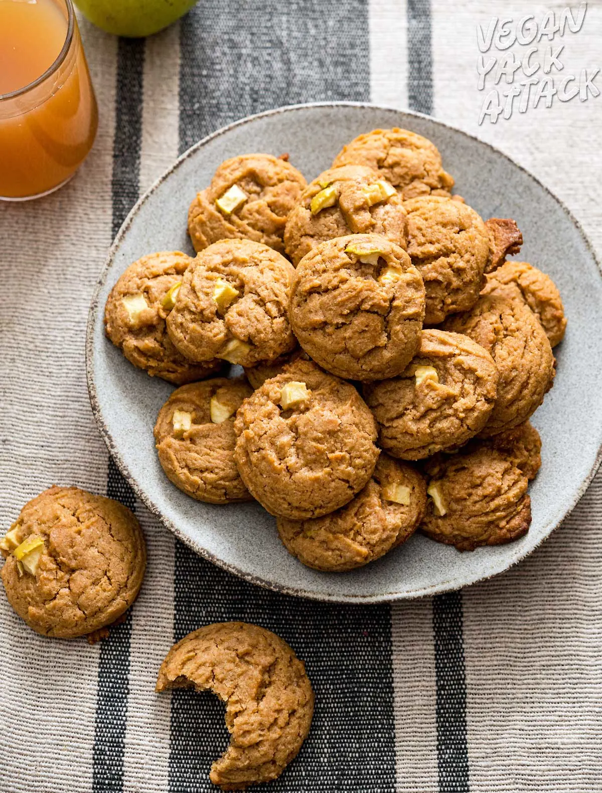 apple cider cookies in a pile on a grey plate next to a mug of cider