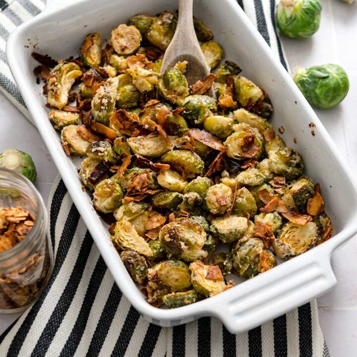 small casserole dish of roasted Brussels sprouts on a striped napkin